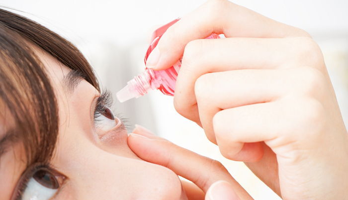 Young woman getting the medicine in the eye