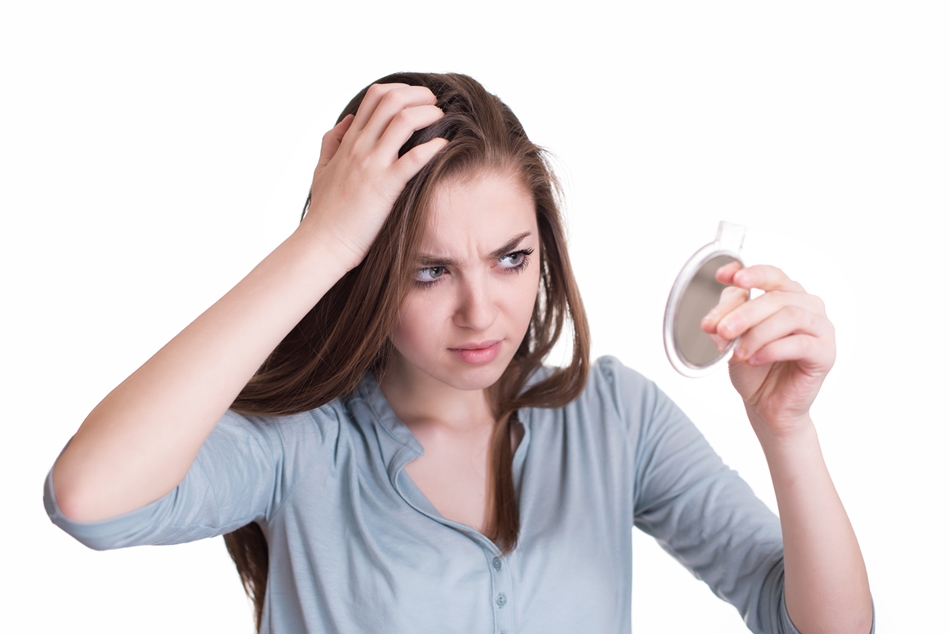 Woman looking at the first grey hair on her scalp