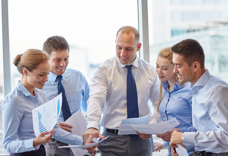business, teamwork, people and technology concept - smiling business team with papers meeting and talking in office